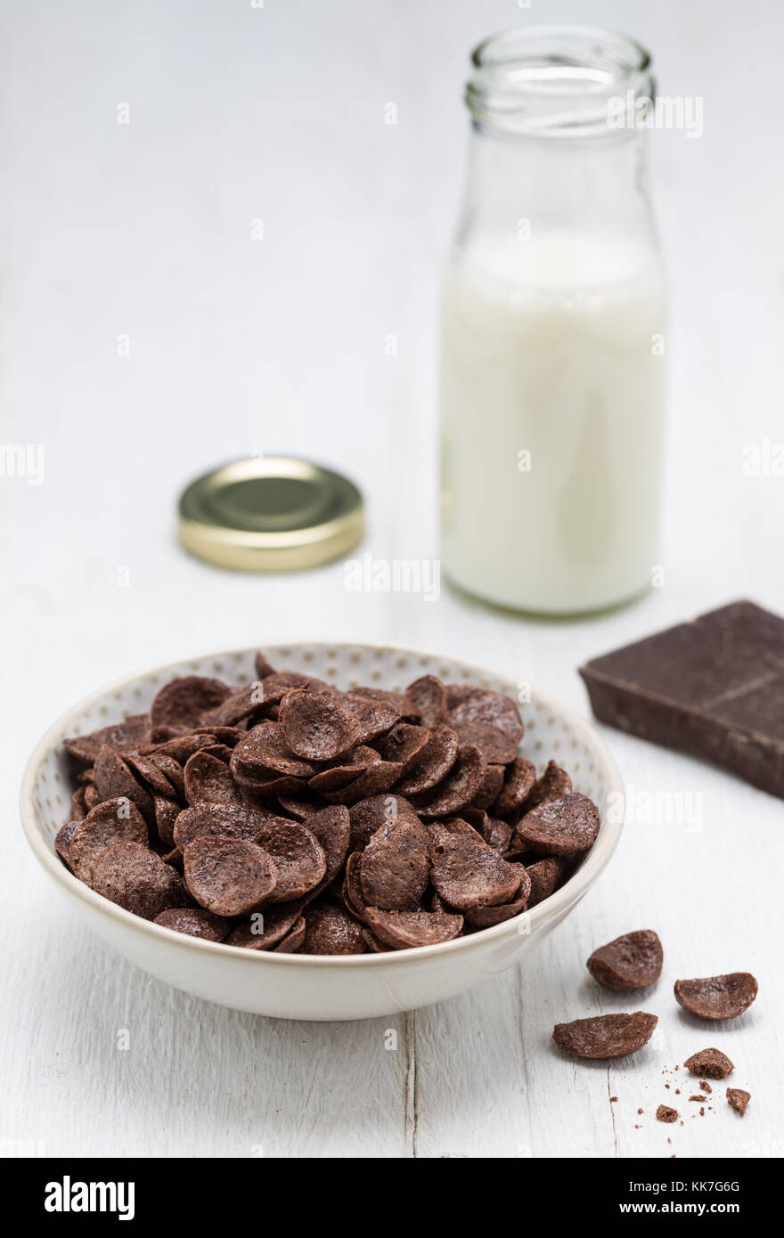 Gocce di cioccolato in fiocchi in una ciotola e bottiglia di latte. Foto Stock