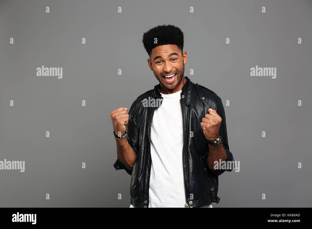 Close-up foto di contentissimo africano stringendo il pugno di vincitore gesto, guardando la telecamera, isolata su uno sfondo grigio Foto Stock