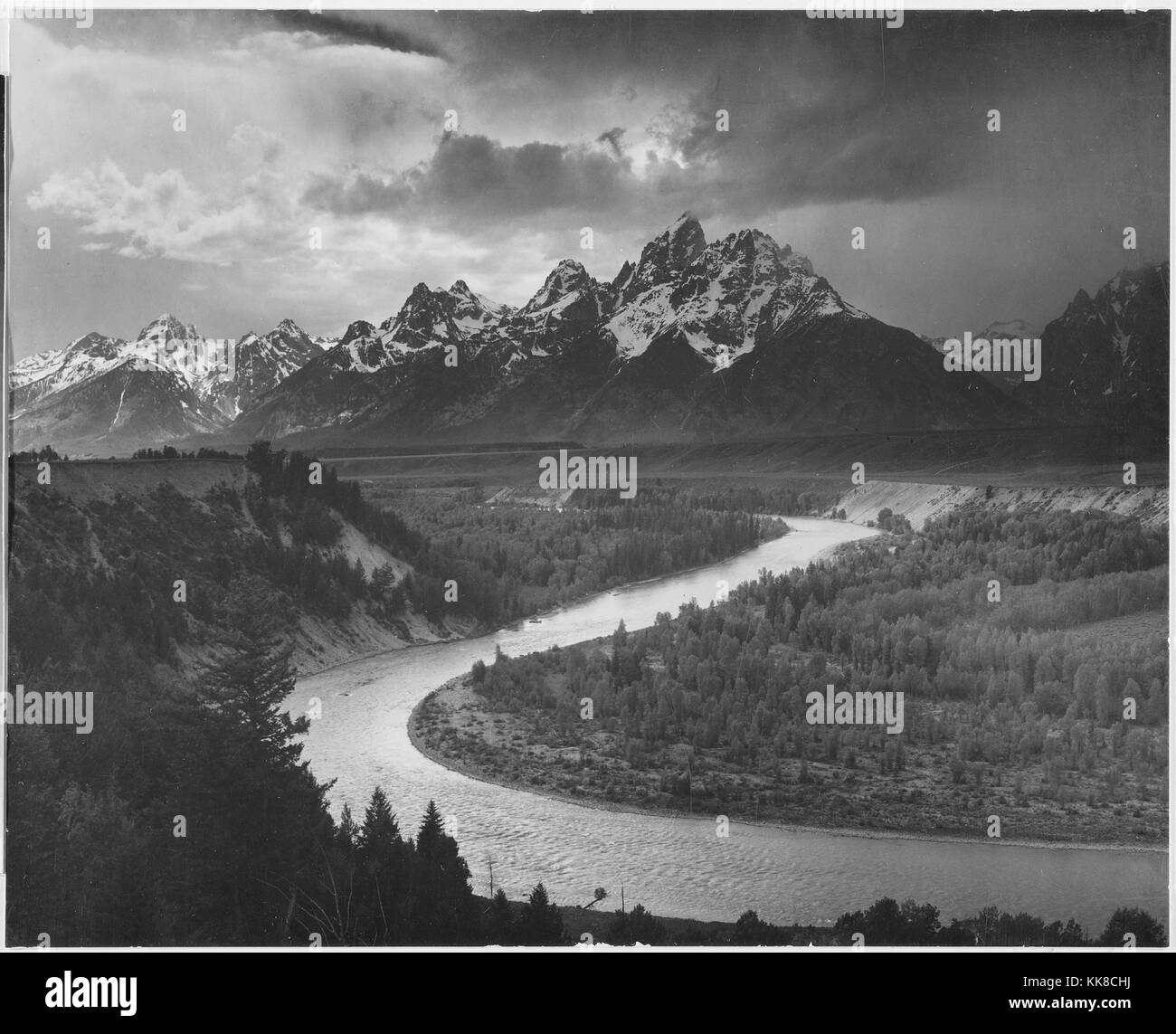 Una fotografia in bianco e nero di diversi dei picchi del Teton Range coperto di neve il Fiume Snake si snoda attraverso il paesaggio ed è circondato da pesantemente terre boschive, l'immagine proviene da una serie di fotografie noto come il progetto murale di Ansel Adams, fu commissionato dal Servizio del parco nazionale nel 1941 per creare un murale fotografico per il dipartimento dell'interno edificio in Washington DC, il progetto è giunto a termine a causa della Seconda Guerra Mondiale, l'immagine cattura una porzione del Grand Teton National Park che è stato istituito nel 1929, Wyoming negli Stati Uniti, 1941. Foto Stock