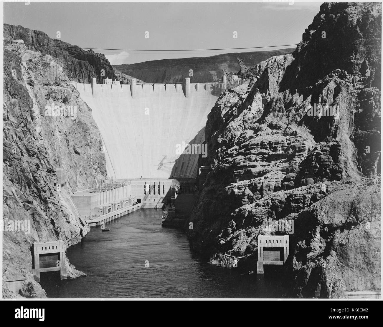 Una fotografia in bianco e nero alla Diga di Hoover, edifici sono che sono parte della diga facility e jet-cancelli di flusso sono visibili in primo piano, la costruzione della Diga di Hoover è stata completata nel 1936, l'immagine proviene da una serie di fotografie noto come il progetto murale di Ansel Adams, fu commissionato dal Servizio del parco nazionale nel 1941 per creare un murale fotografico per il dipartimento dell'interno edificio in Washington DC, il progetto è giunto a termine a causa della Seconda Guerra Mondiale, gli Stati Uniti, 1941. Foto Stock