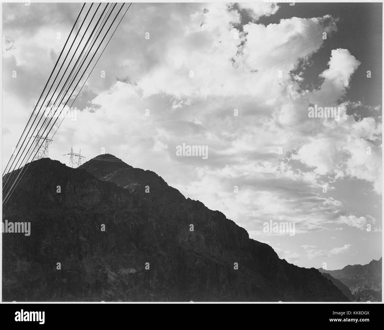 Una fotografia in bianco e nero di una montagna e linee di trasmissione vicino alla Diga di Hoover, torri per le linee di trasmissione può essere visto sul picco di una montagna, l'immagine proviene da una serie di fotografie noto come il progetto murale di Ansel Adams, fu commissionato dal Servizio del parco nazionale nel 1941 per creare un murale fotografico per il dipartimento dell'interno edificio in Washington DC, il progetto è giunto a termine a causa della Seconda Guerra Mondiale, gli Stati Uniti, 1941. Foto Stock