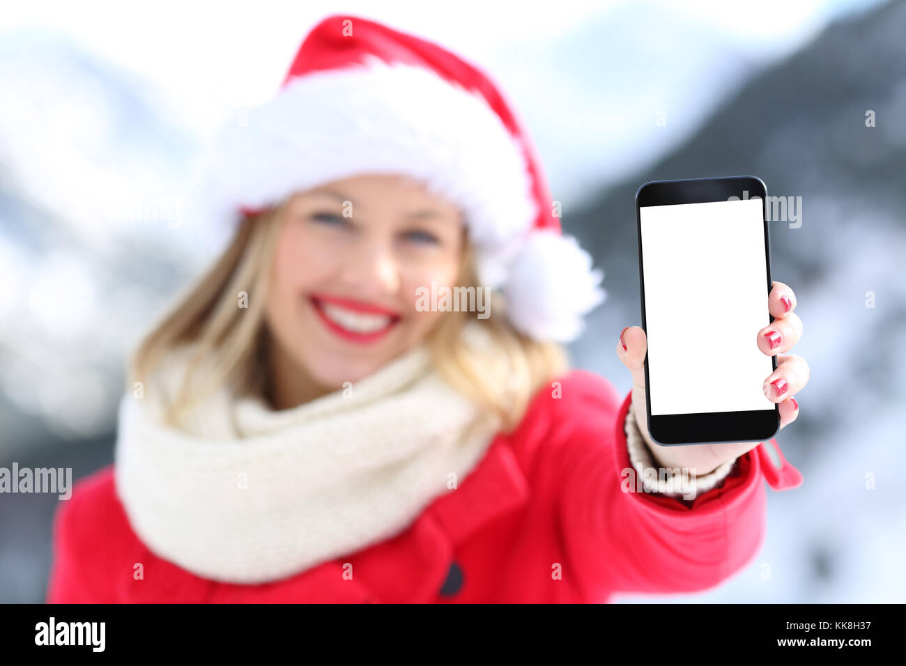 Ragazza di vacanze di Natale che mostra lo schermo del telefono con una montagna innevata in background Foto Stock