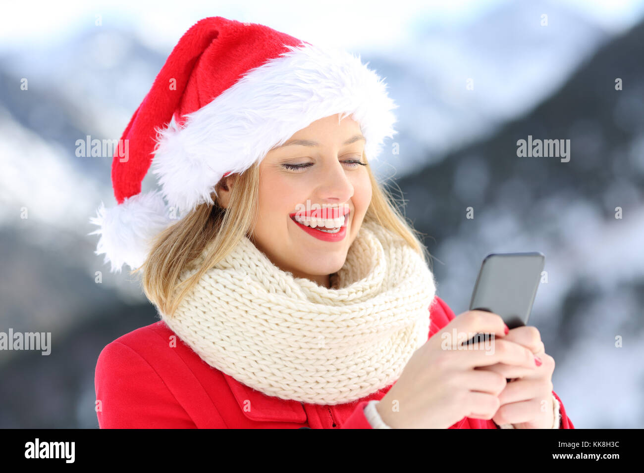 Happy girl su vacanze di Natale utilizzando smart phone con una montagna innevata in background Foto Stock