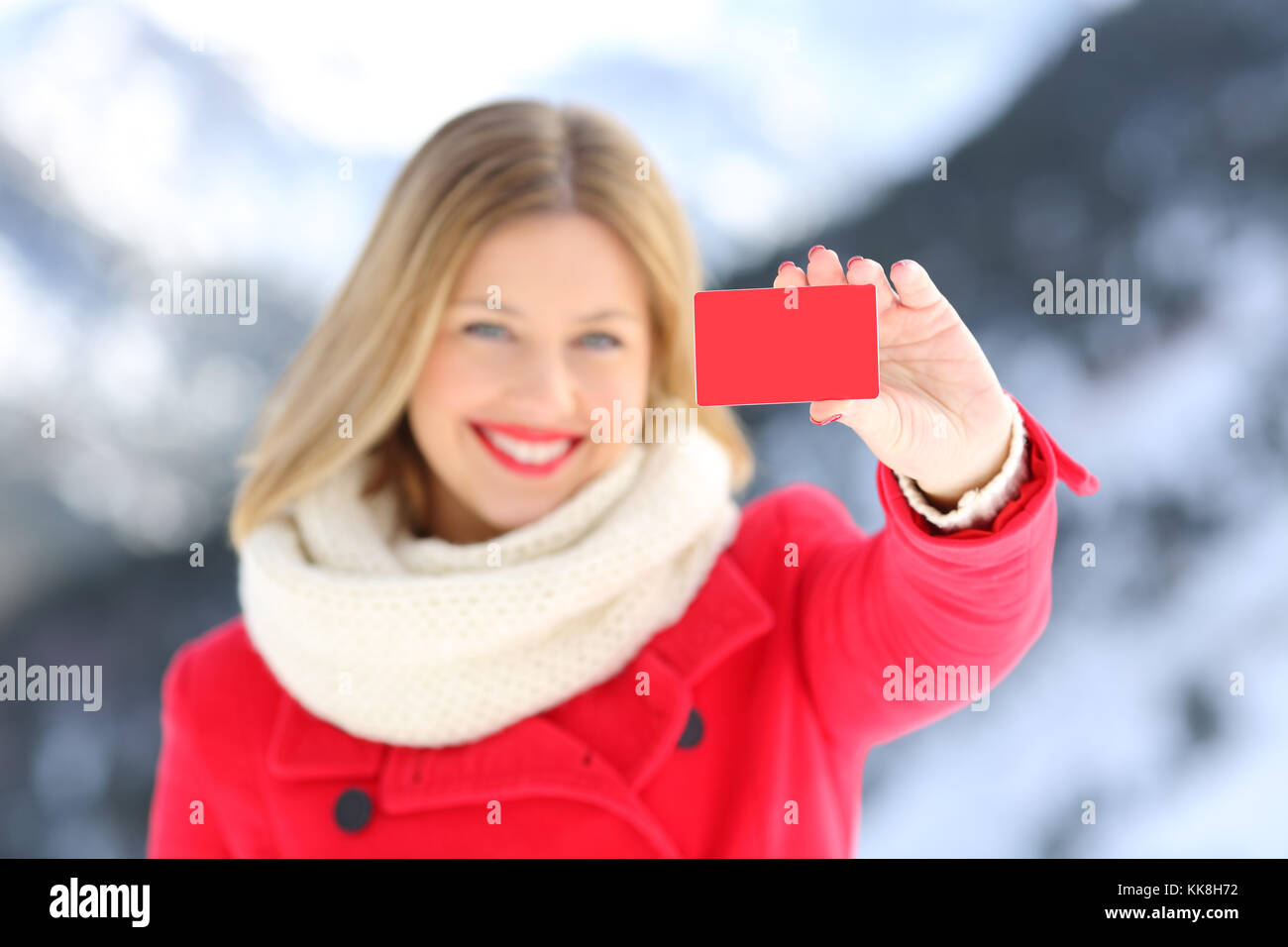 Vista frontale il ritratto di una donna che mostra una carta di credito in inverno con una montagna innevata in background Foto Stock