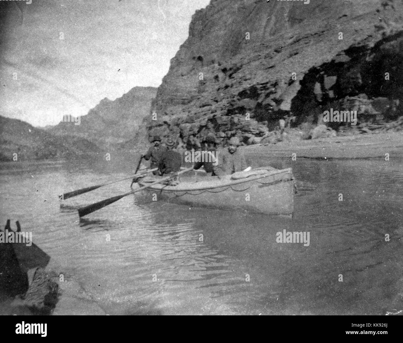 Una fotografia di un gruppo di quattro uomini in viaggio in barca a remi attraverso il Grand Canyon, si trovano appena al di sotto di un tratto del fiume Colorado conosciuta come paria Riffle, Arizona, 1905. Dalla Biblioteca Pubblica di New York. Foto Stock