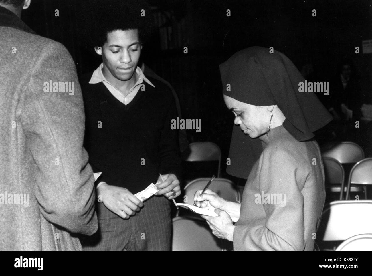 Fotografia in bianco e nero di Sonia Sanchez, poeta afro-americano più spesso associati con il Black Arts movimento, era un destinatario di 1993 Pew borse di studio nel campo delle arti, in piedi con due uomini, firma un autografo, 1972. Dalla Biblioteca Pubblica di New York. Foto Stock