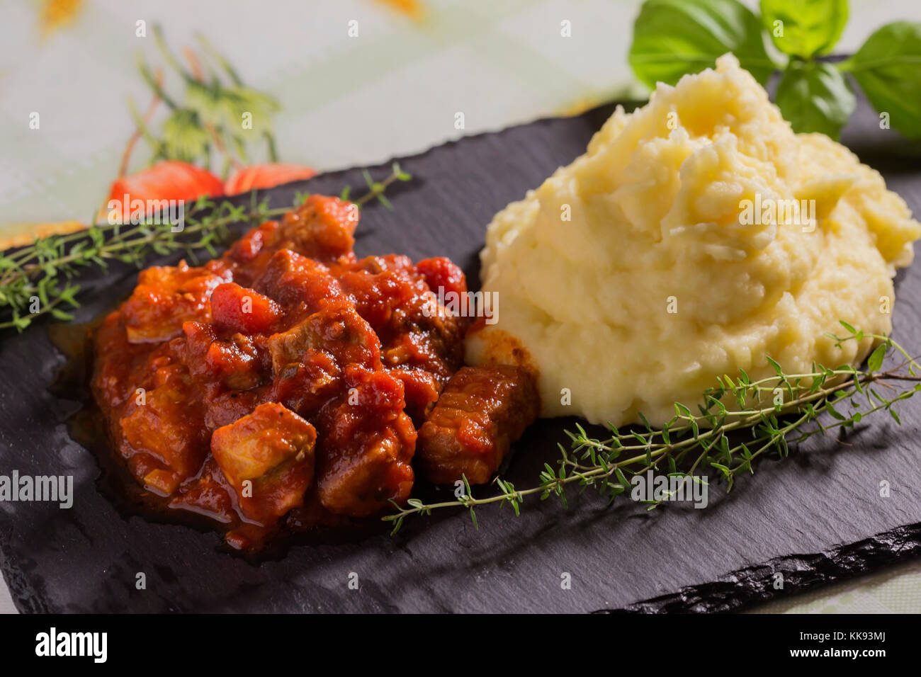 Spezzatino di maiale in salsa di pomodoro con purè di patate e le erbe aromatiche Foto Stock