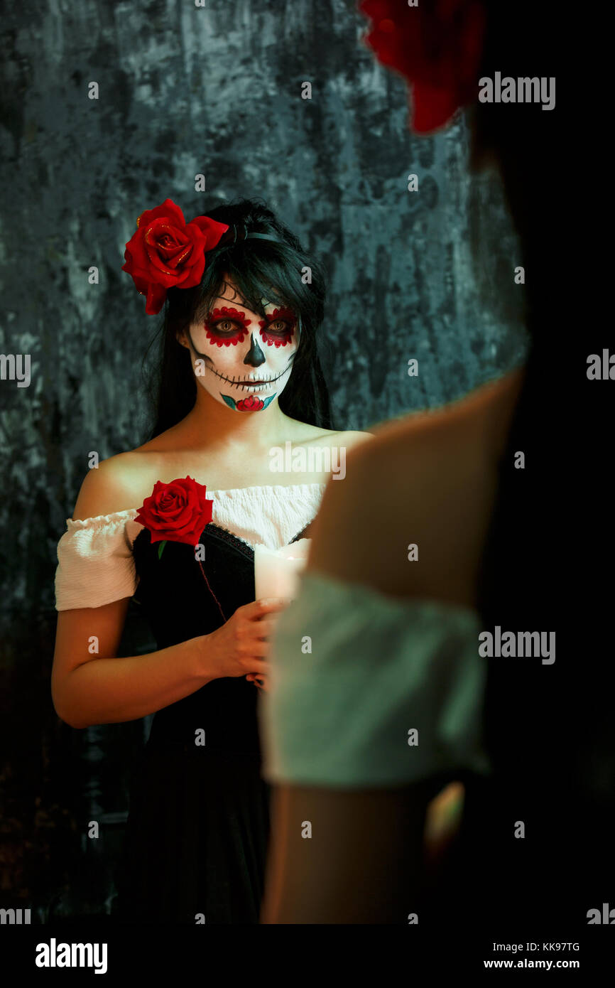 Foto di halloween di donna con il trucco sulla faccia con fiori di colore rosso Foto Stock
