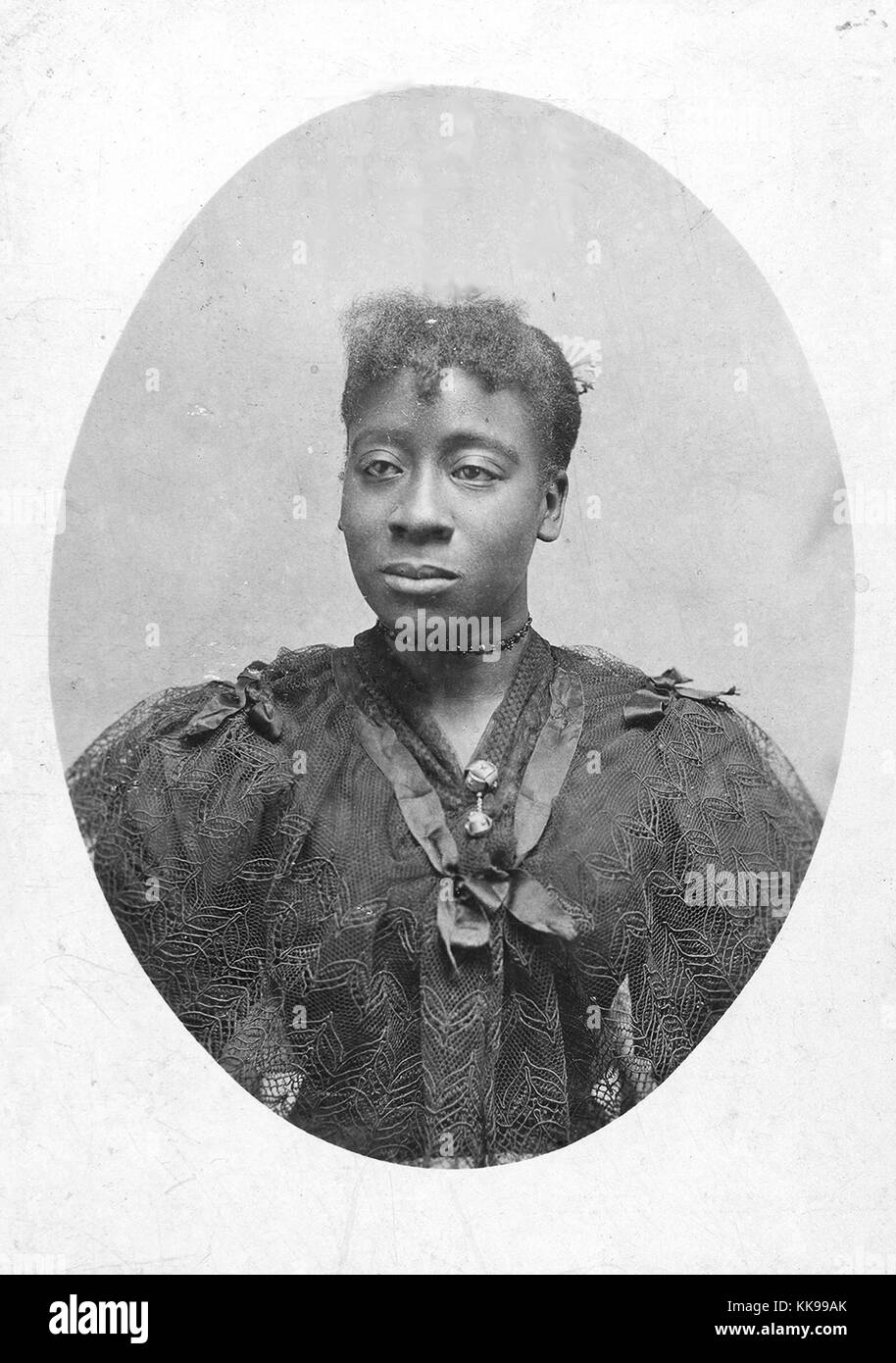 Un ritratto fotografico di una donna non identificato, indossava un abito scuro che è pura copertura di pizzo il corpetto, ella è anche indossando un girocollo e ha un fiore nei suoi capelli, 1900. Dalla Biblioteca Pubblica di New York. Foto Stock