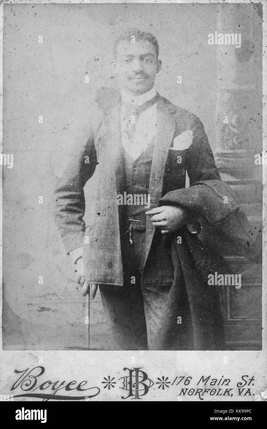 Seppia studio fotografia di un uomo afro-americano, tre quarti di lunghezza, indossa una tuta, umettare posato sul suo braccio e la canna da zucchero in mano, segnato, in fondo, Boyce, Norfolk, Virginia, 1900. Dalla Biblioteca Pubblica di New York. Foto Stock