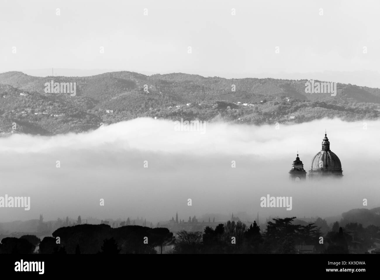 Splendida vista su Santa Maria degli Angeli chiesa papale (Assisi) metà coperti dalla nebbia all'alba Foto Stock