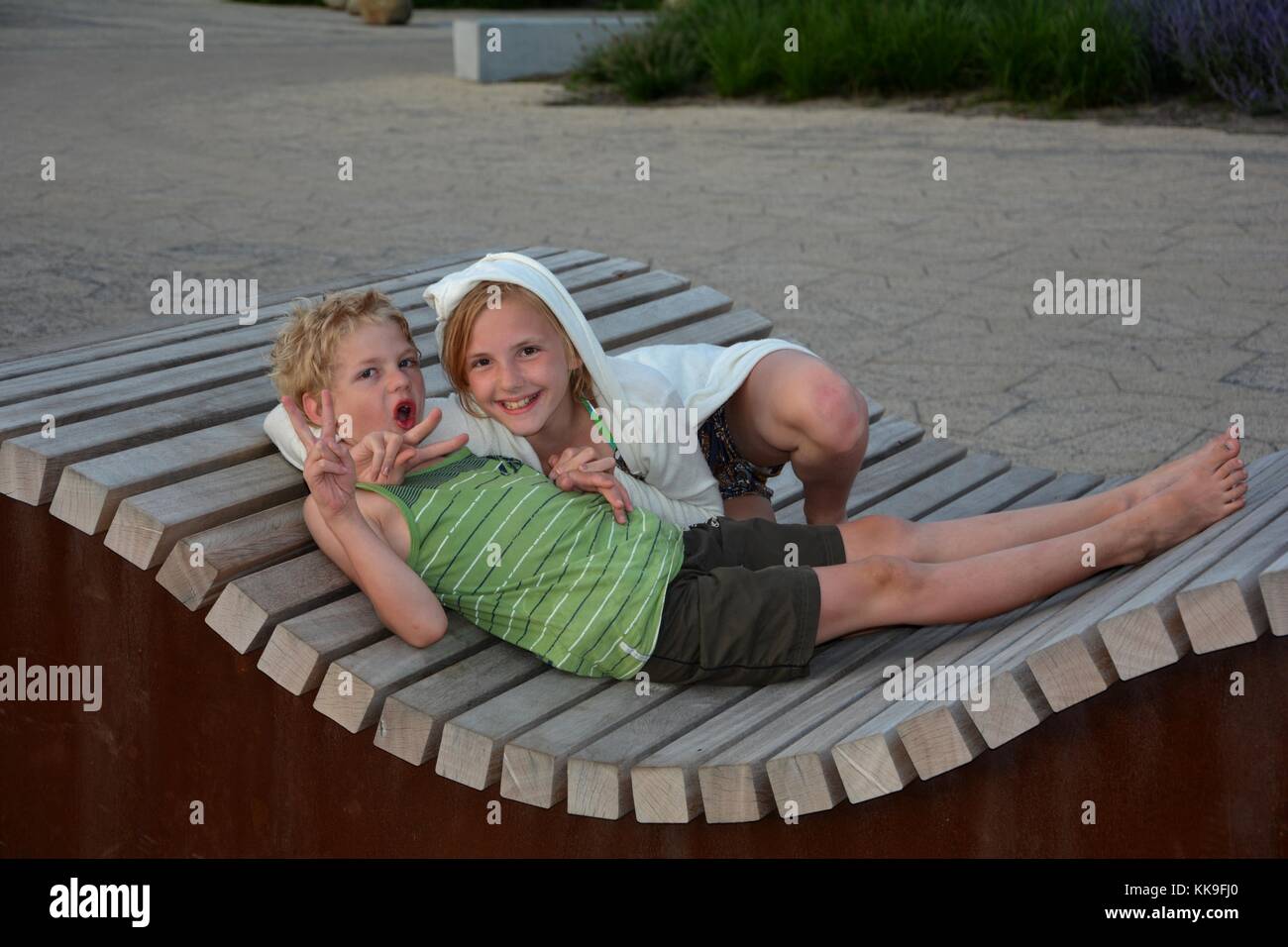 Due bambini di sedersi sul banco ondulato e rendere divertente movimento della mano Foto Stock