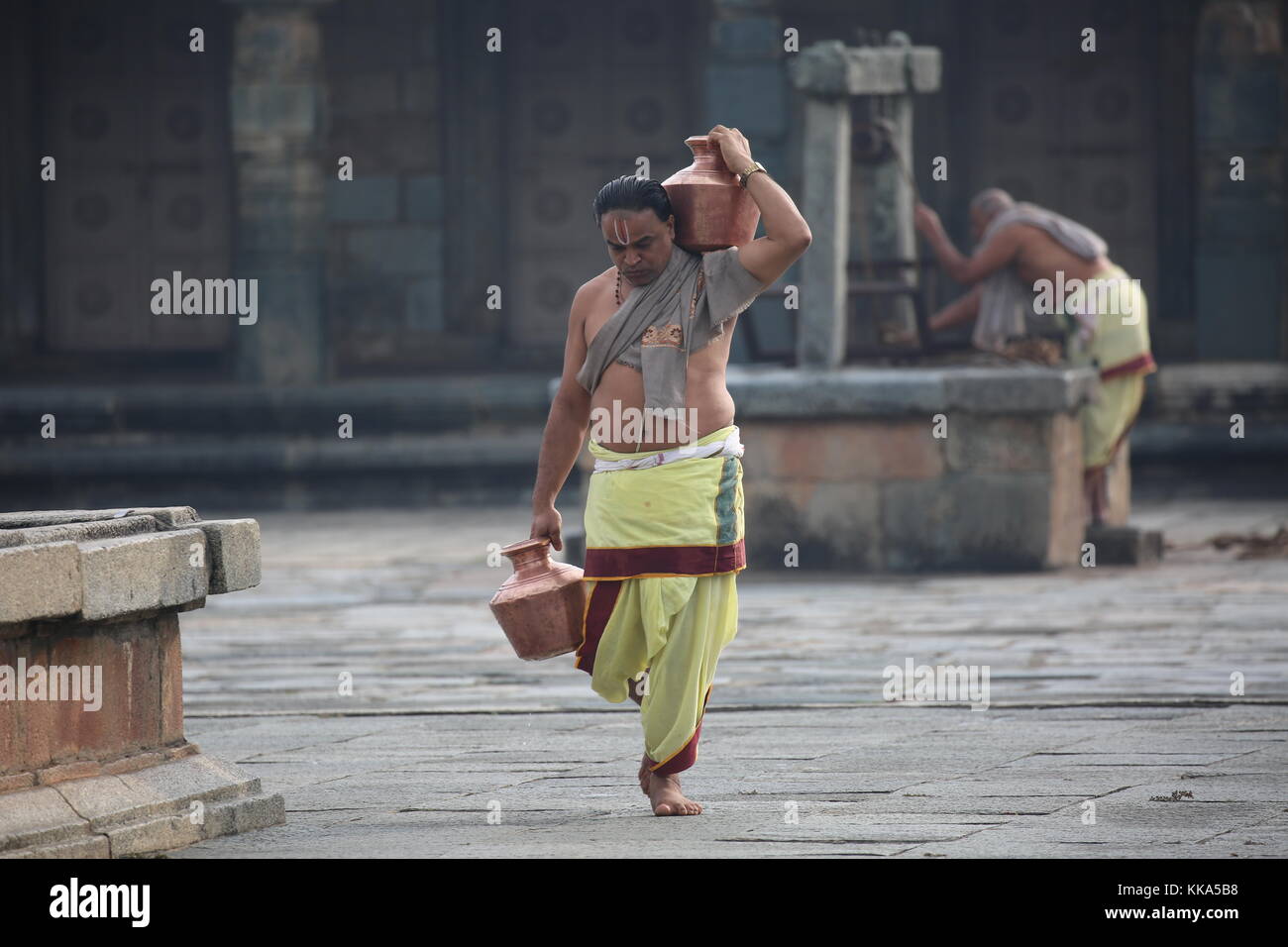 Mattina in Chenna Keshava Vishnu Temple - Sacerdote con lota kalash pot facendo offerte - Priester Kuferkrug mit Wasser beim holen Foto Stock
