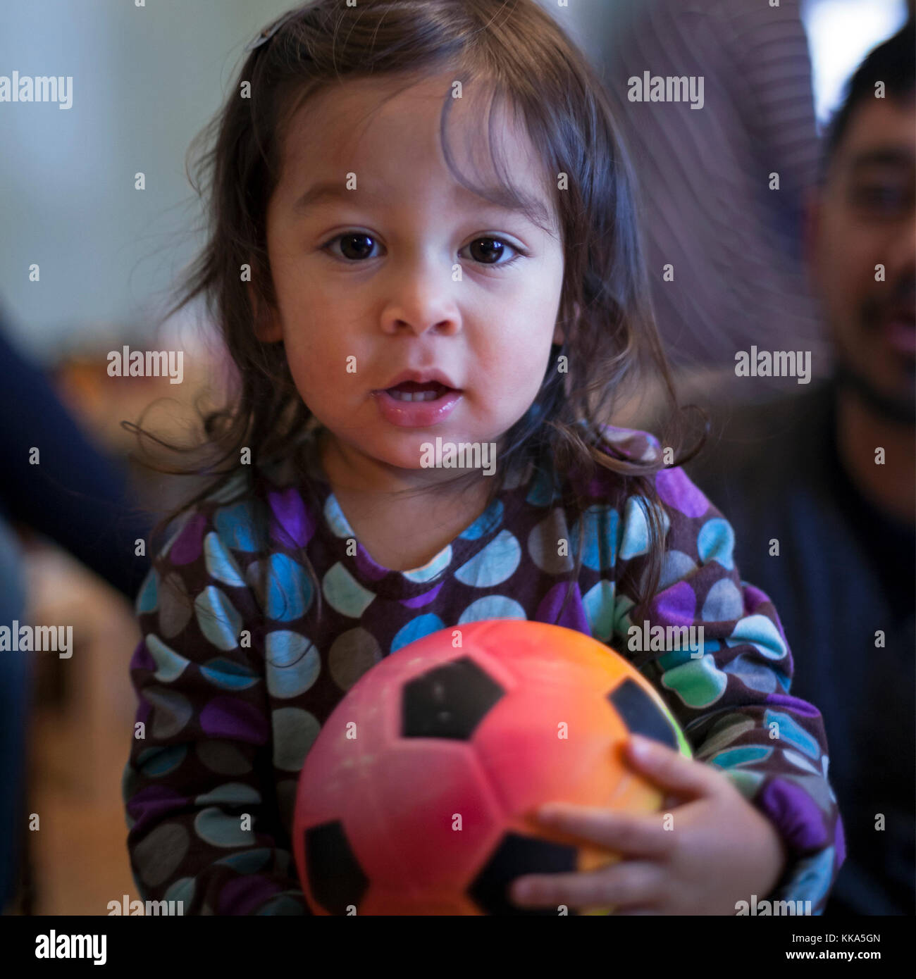 Una ragazza di 2 anni tiene la sua palla di calcio. Foto Stock