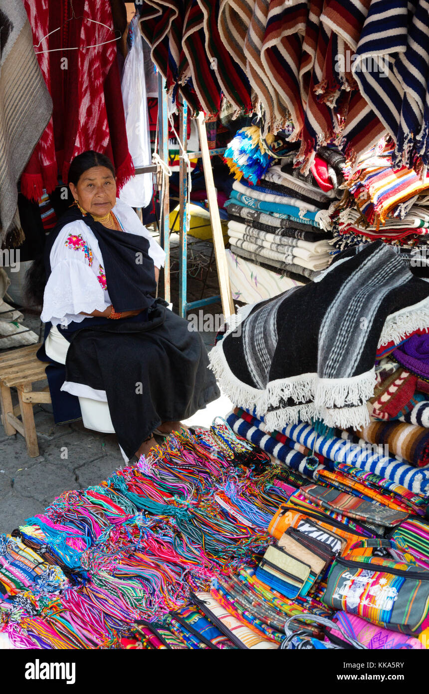 Stallo di tessili e donna indigena stallholder; Mercato di Otavalo Ecuador America del Sud Foto Stock