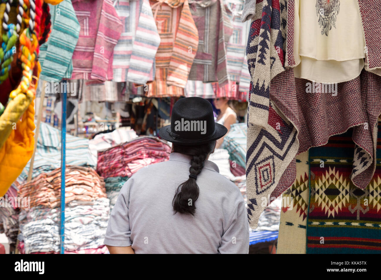 Uomo indigeni che indossa un cappello e con coda di cavallo come titolare di stallo ad un mercato in stallo, Mercato di Otavalo, Ecuador America del Sud Foto Stock