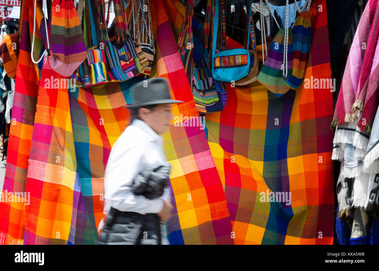 Mercato di Otavalo Ecuador - un uomo indigeni passando un colorato tessili stallo, Quito, Ecuador, America Latina Foto Stock