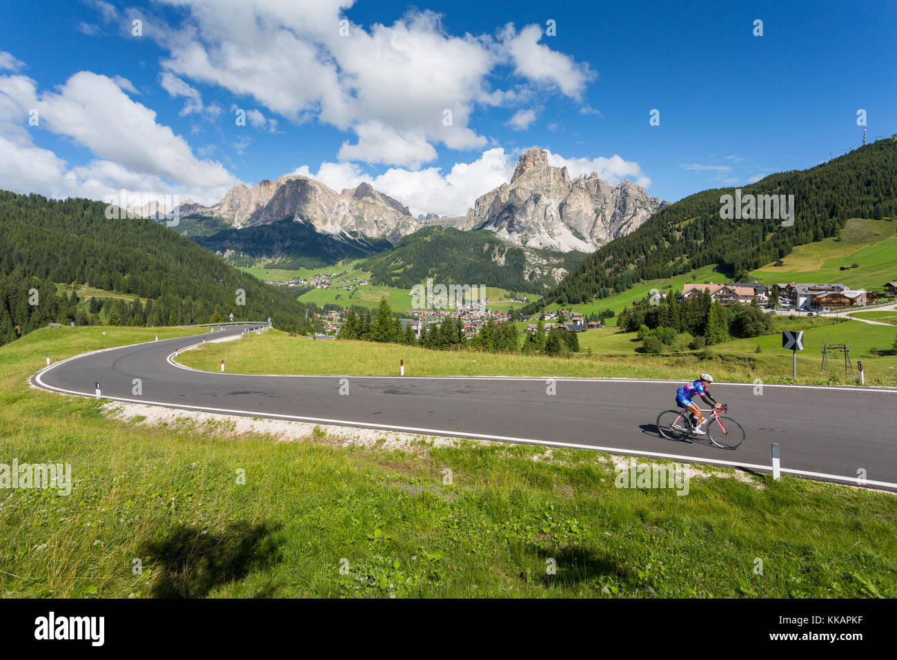 Vista verso Corvara e ciclista su strada, Alta Badia, Corvara Dolomiti, Alto Adige, Italia, Europa Foto Stock