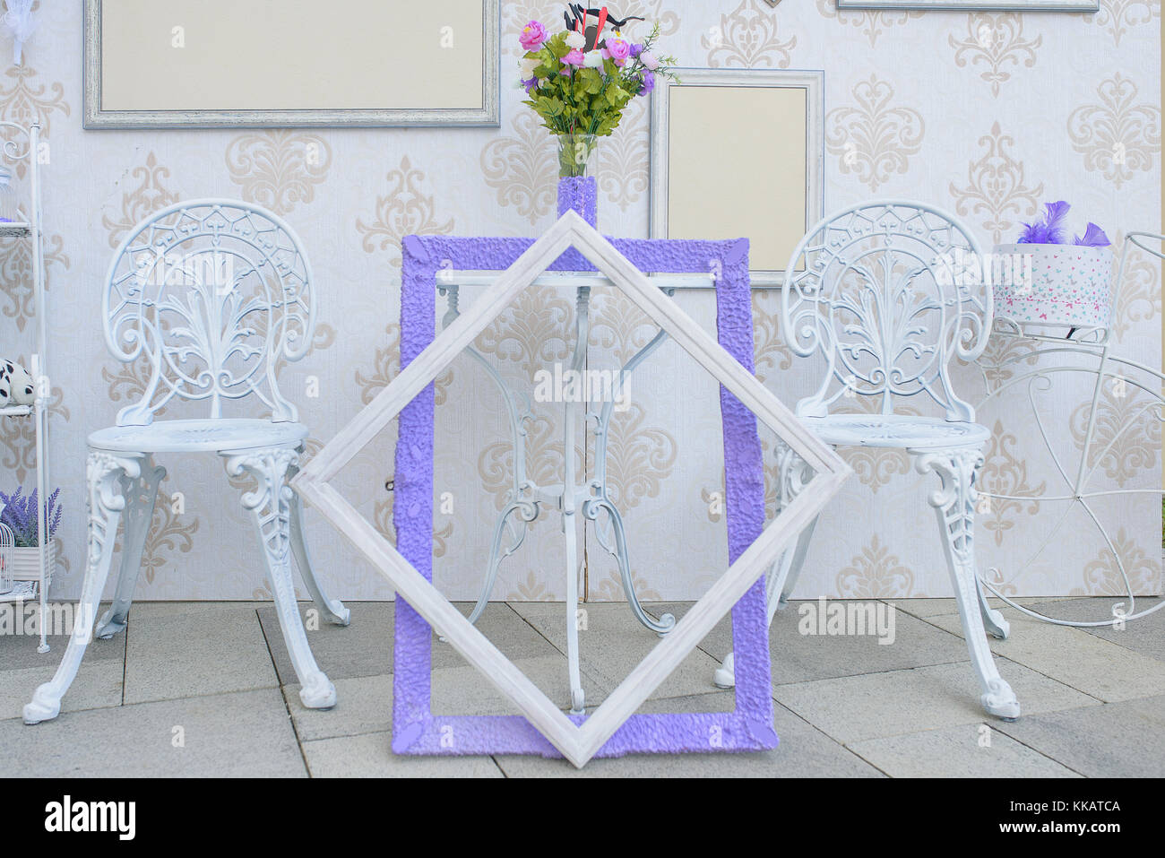 Bianco esterno mobili in ferro e vuoto cornici con accenti di colore viola, interessante display minimalista per ricevimenti per matrimoni o feste in giardino Foto Stock