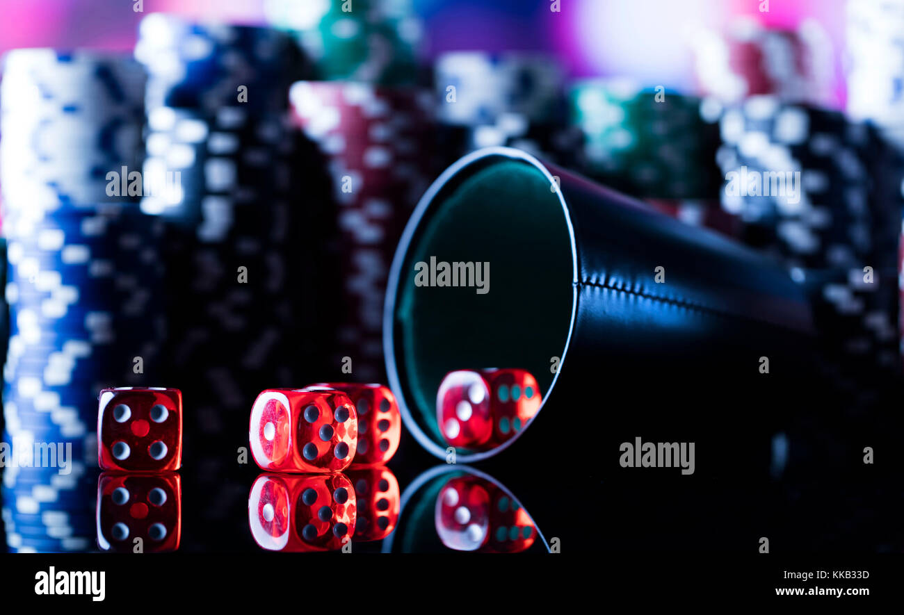 Casino tema. Alto contrasto immagine del casino roulette, poker, gioco di dadi, Poker chips su un tavolo da gioco, tutti su colorato sfondo bokeh di fondo. Foto Stock