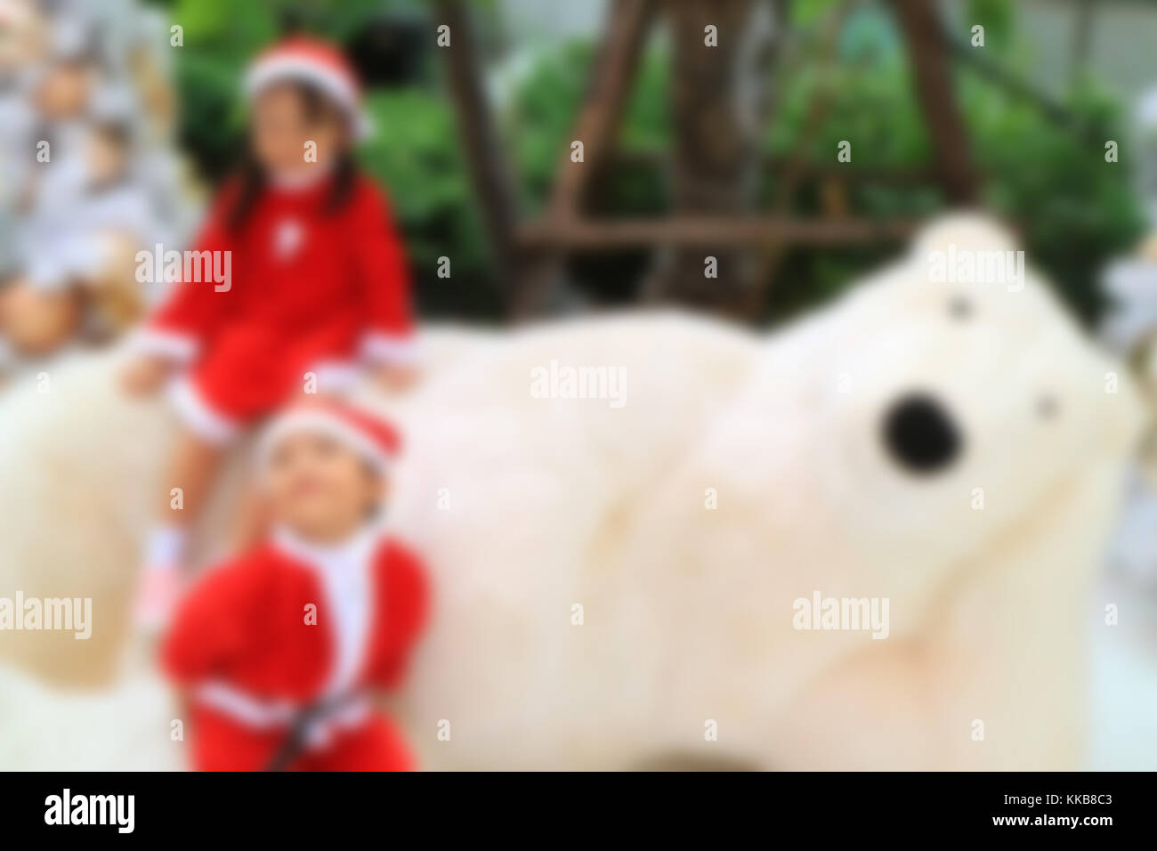 Al di fuori della messa a fuoco immagine del piccolo ragazzo e ragazza di carino santa abiti giocando con un gigantesco orso polare toy Foto Stock