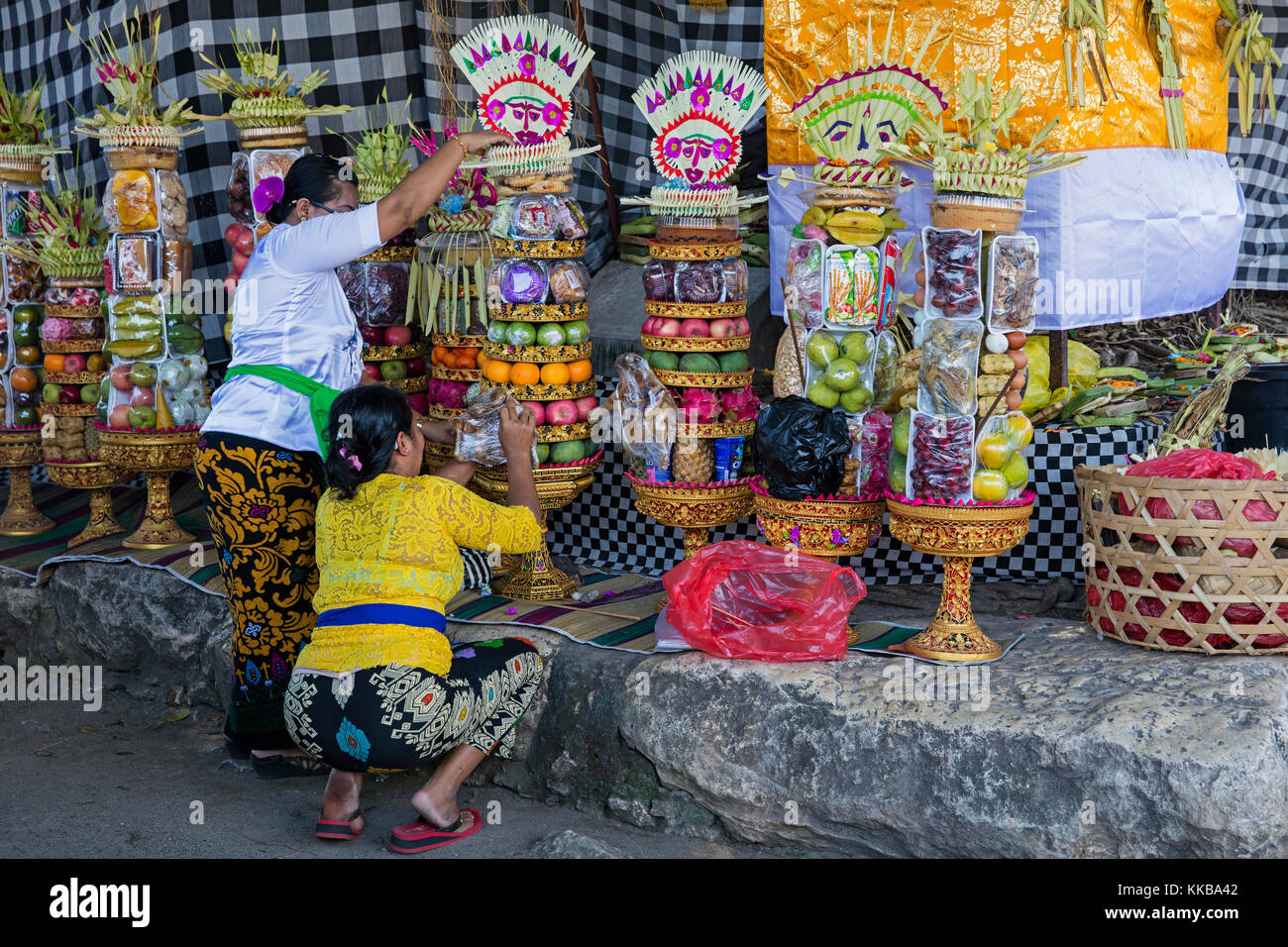 Donne indonesiane preparare offerte / gebogans per cerimonia al grande banyan tree sull'isola Nusa Lembongan vicino a Bali, in Indonesia Foto Stock