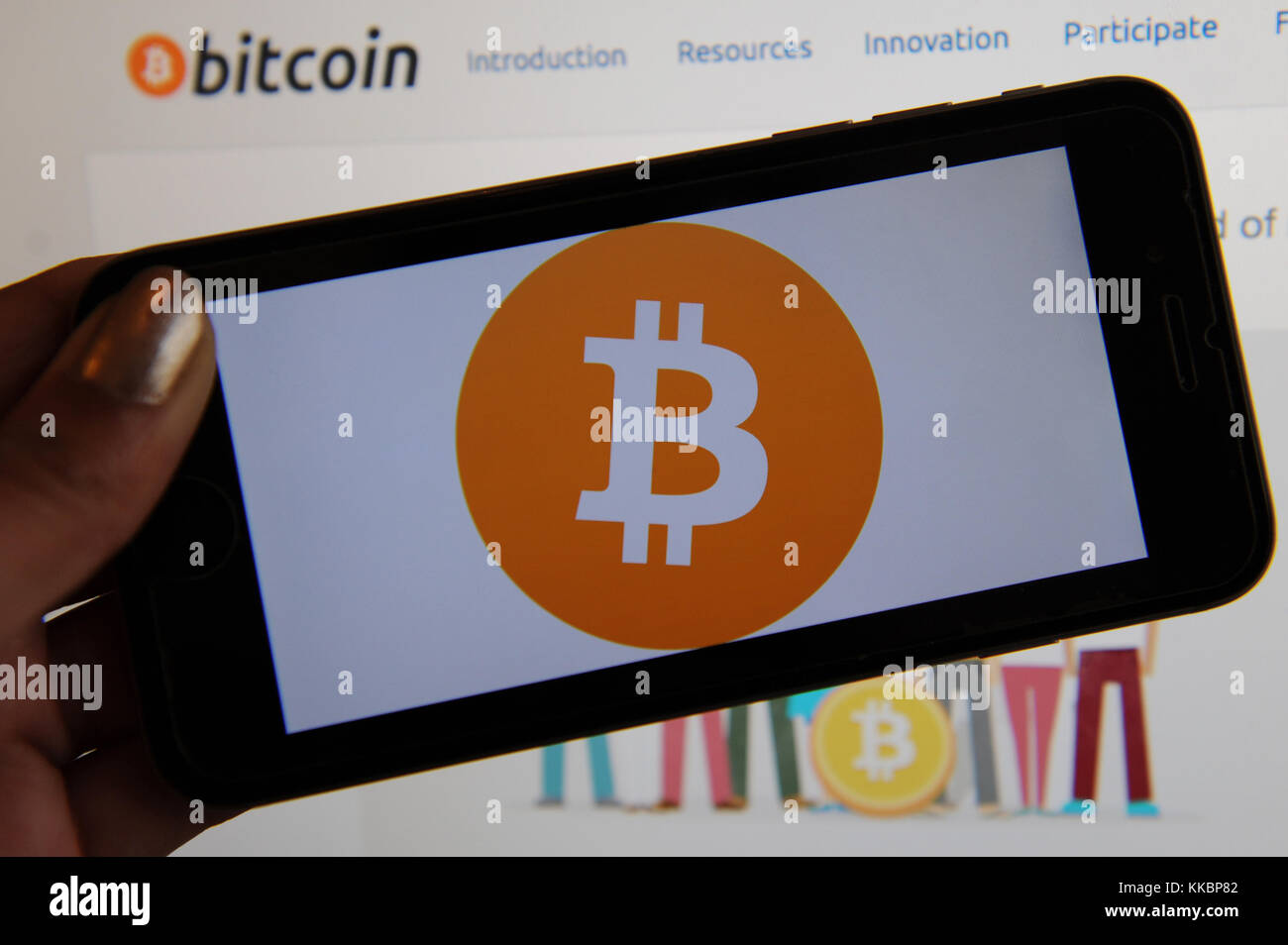 Il logo bitcoin è visto su una schermata telefono e il sito web bitcoin è visto su un computer dietro. bitcoin è un cryptocurreny. Foto Stock