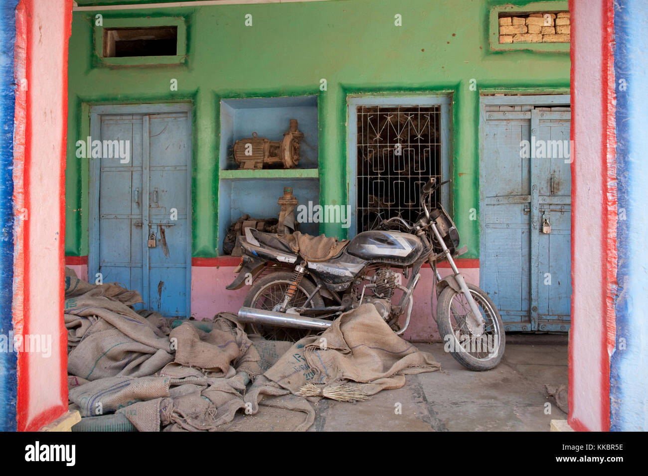 Una moto al di fuori di un dipinto luminosamente shop in un villaggio vicino a Bijaipur, Rajasthan, India Foto Stock