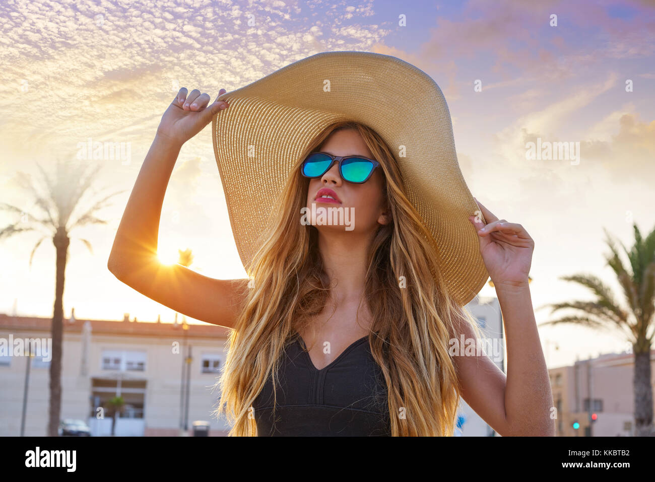 Blonde teen ragazza occhiali da sole e pamela cappello per il sole a Palm  tree tramonto Foto stock - Alamy