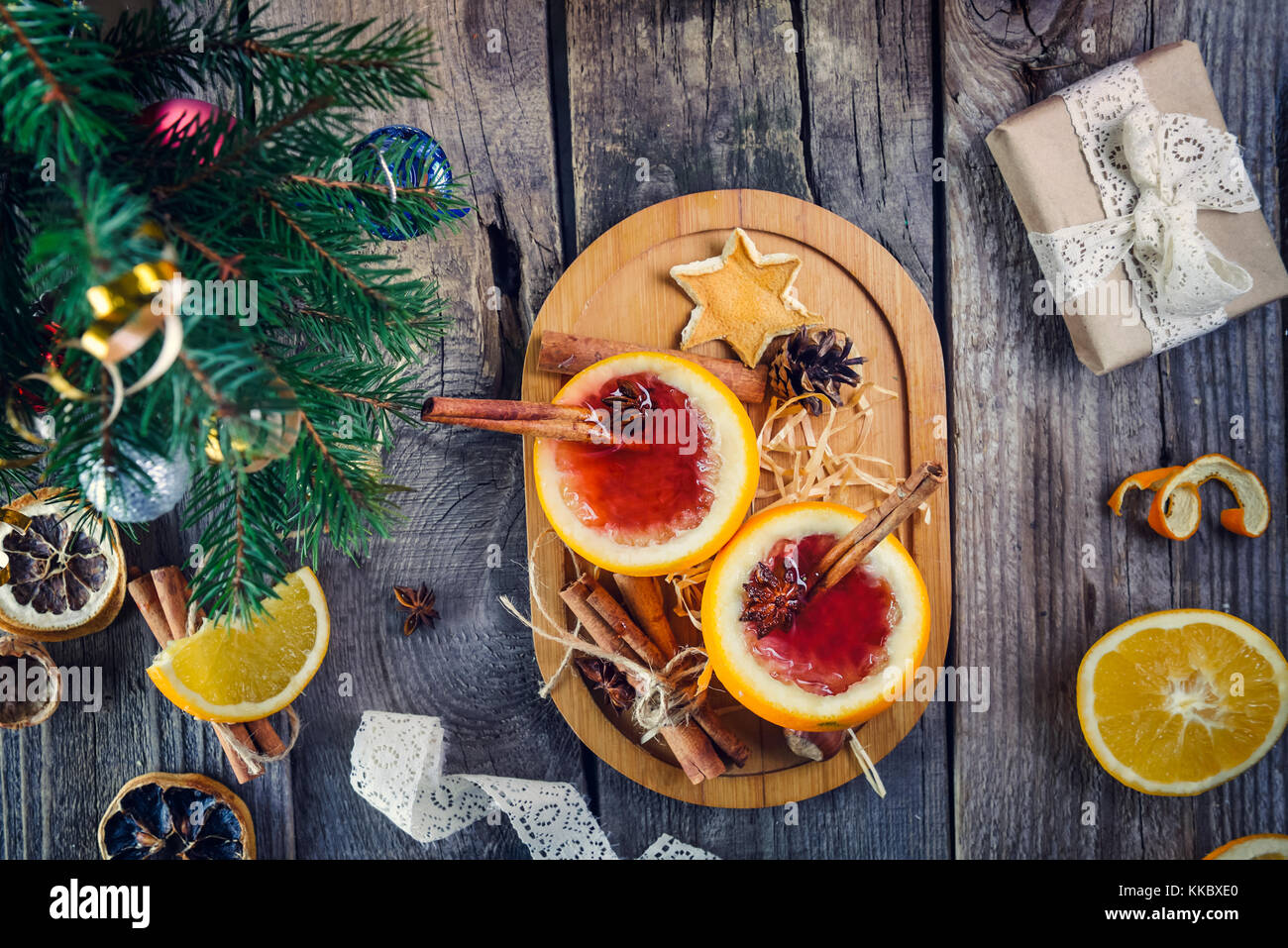 Natale vin brulé - insoliti servita in arancione. calda inverno drink con frutti di bosco, arancia, spezie, cannella sul vecchio tavolo in legno con doni, Abete rami, Foto Stock