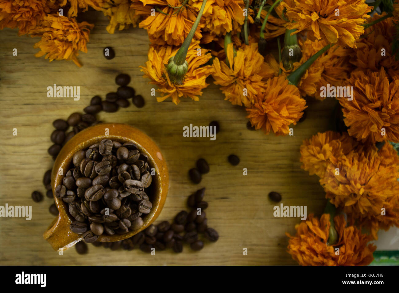 Vista dall'alto di chicchi di caffè all'interno di un messicano fatto a mano tazza circondato da fiori di colore giallo Foto Stock