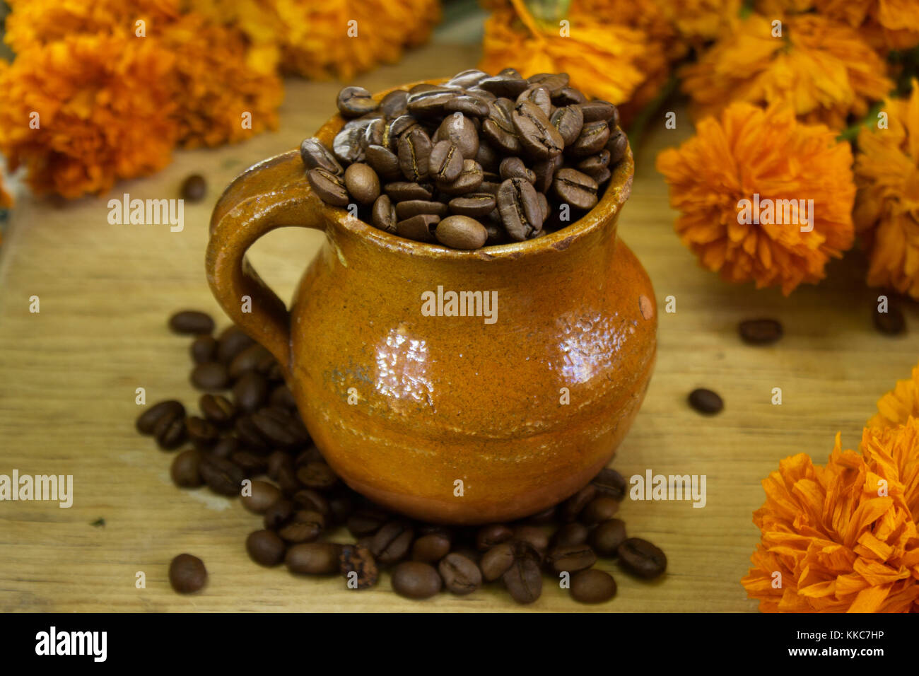 I chicchi di caffè all'interno di un messicano fatto a mano tazza circondato da fiori di colore giallo Foto Stock