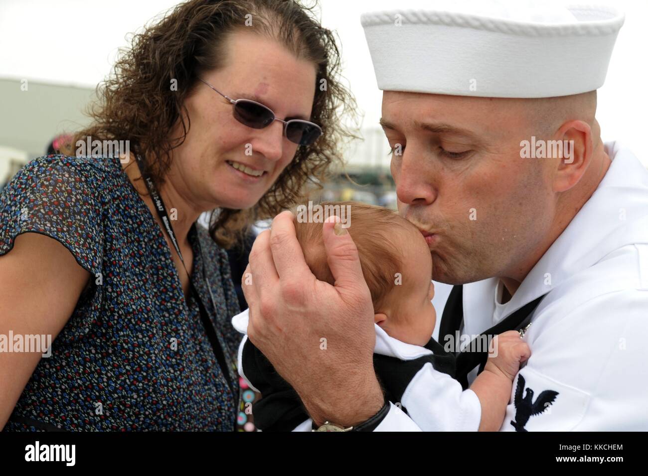 Tessa Ooley guarda suo marito, gas turbine Systems Technician 1st Class Daniel Ooley assegnato al cacciatorpediniere missilistico guidato USS Halsey DDG 97, baciare sua figlia per la prima volta durante una festa di ritorno a casa alla base navale di San Diego, San Diego. Per gentile concessione di Mass Communication Specialist 2nd Class Rosalie Garcia/US Navy. 2012. Foto Stock