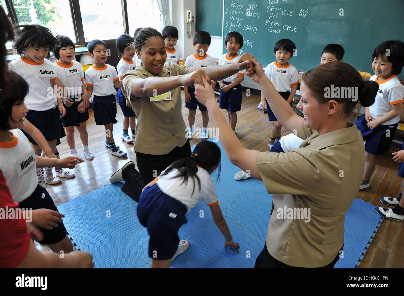 Hull Maintenance Technician 3rd Class Jane Clark and Boatswain's Mate Seaman Brittany Chiles, assegnato al cacciatorpediniere missilistico guidato classe Arleigh Burke USS McCampbell DDG 85, giocano un gioco con i primi classificati della Ogamo Elementary School, Shimoda, Giappone. Per gentile concessione di Seaman Declan Barnes/US Navy, specialista della comunicazione di massa. 2012. Foto Stock