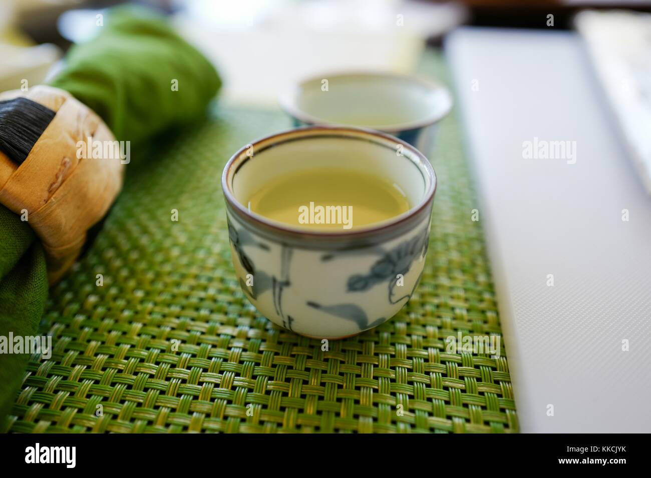 Vista ravvicinata di un bicchiere di vino giapponese di riso sakè su un tappeto intrecciato, con tovagliolo e supporto visibili, 2016. Foto Stock