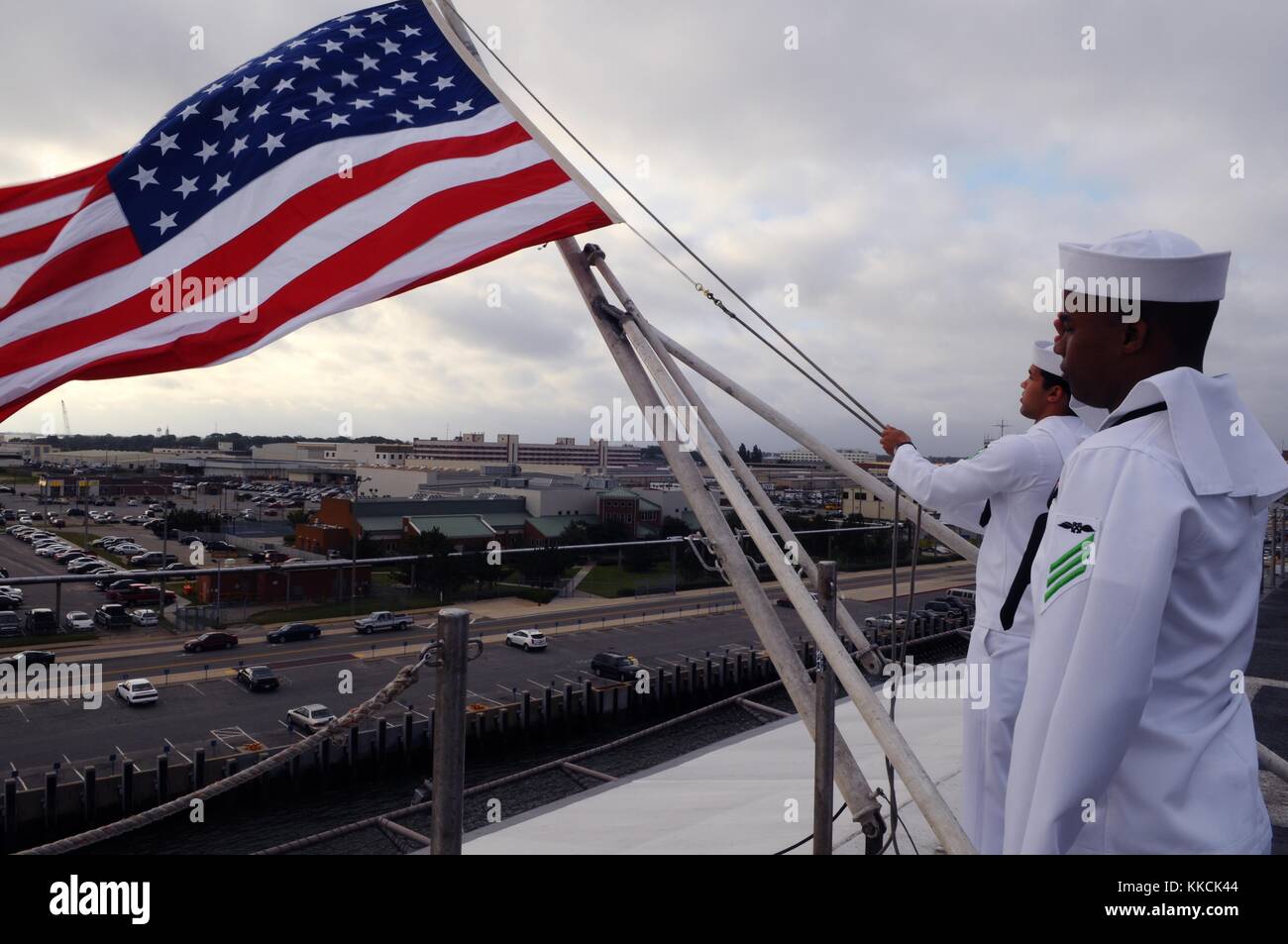 Aviation Boatswain's Mate Handling Airman Jackie L Chess, Right, saluta come Aviation Boatswain's Mate Handling Airman Jose A Dominguez Rodriquez alza la bandiera americana durante una commemorazione del Memorial Day sul ponte di volo della portaerei USS George HW, Norfolk. Per gentile concessione di Mass Communication Specialist 3rd Class Derrik Noack/US Navy, 2012. Foto Stock