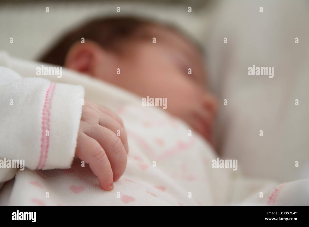 Baby girl dormire al di fuori della messa a fuoco e la sua piccola le mani nel fuoco. Foto Stock