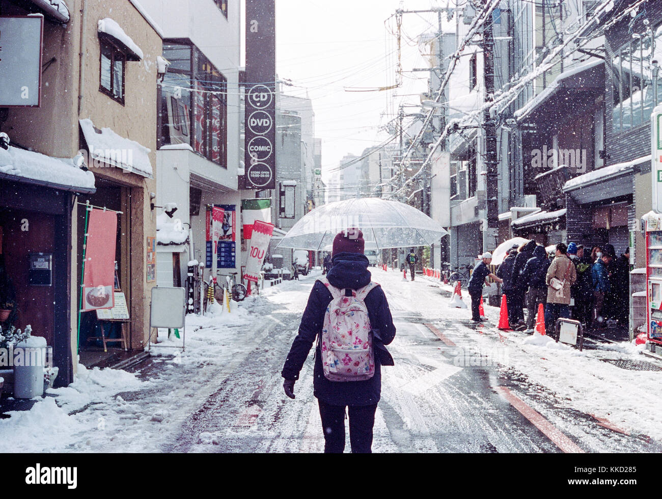 Ragazza con ombrello e camminare attraverso la strada innevata a Kyoto, Giappone in inverno Foto Stock