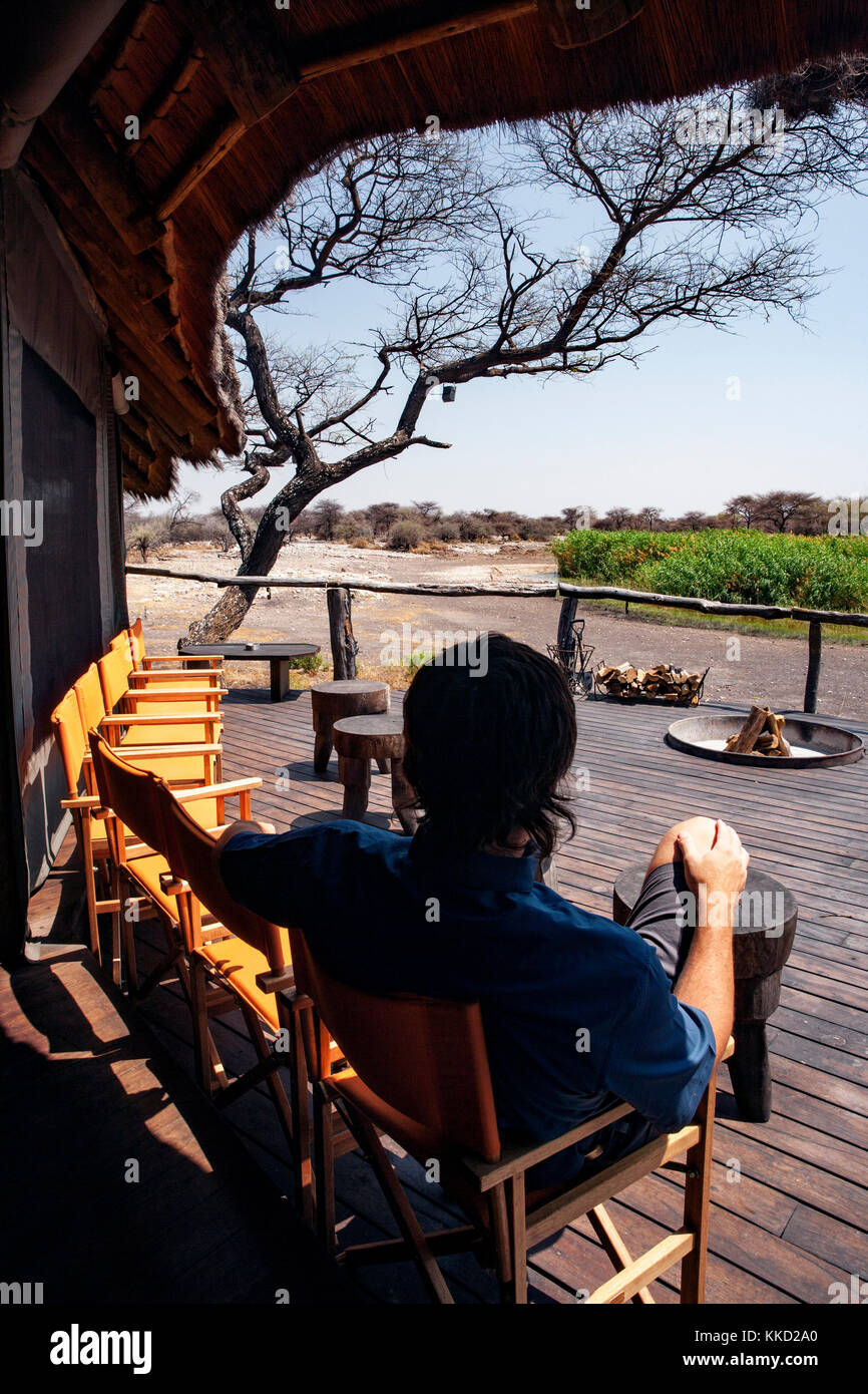 Persona seduta sul ponte a onguma tree top camp, onguma Game Reserve, Namibia, Africa Foto Stock