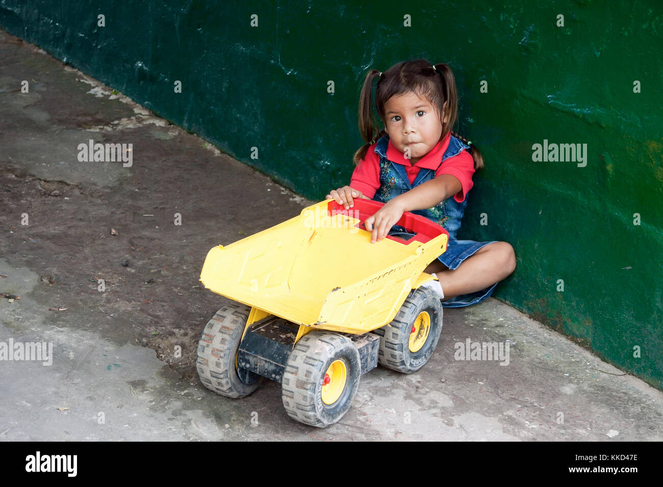 Canaima, Venezuela, 11 novembre 2010: indigeni pemon bambina gioca con il giocattolo carrello accanto alla parete rustico Foto Stock