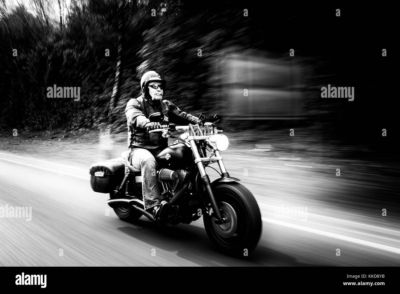 Uomo con un manubrio di baffi a cavallo di un Harley Davidson Moto con sfocatura del movimento Foto Stock