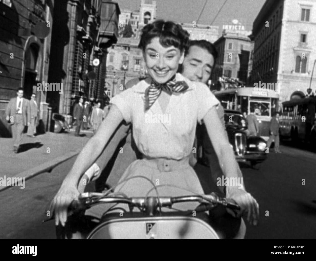 Un'immagine del film "Vacanze Romane", con Audrey Hepburn e Gregory Peck a bordo di una Vespa per le strade di Roma, catturando il momento iconico del classico film comico romantico del 1953. Foto Stock