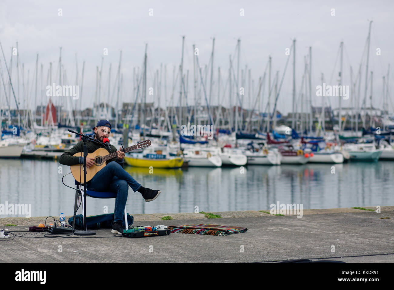 L'uomo musicista di strada su un Howth è pier a suonare e cantare canzoni romantiche per passare dai turisti. La penisola di Howth, Dublino, Irlanda Foto Stock