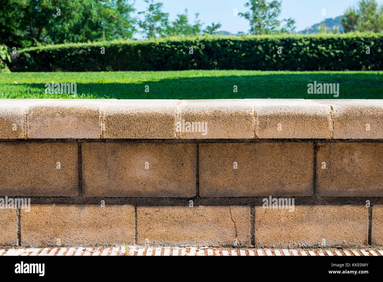 Pietra di recinzione bassa contro uno sfondo di prato verde Foto Stock