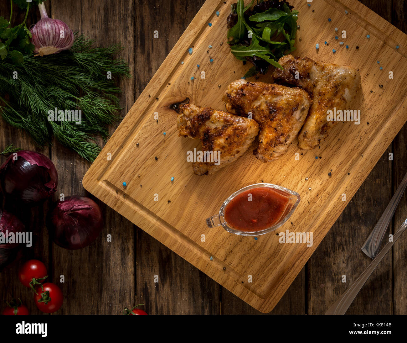 Alette di pollo fritte decorato con verdure su un vassoio in legno, vista dall'alto Foto Stock