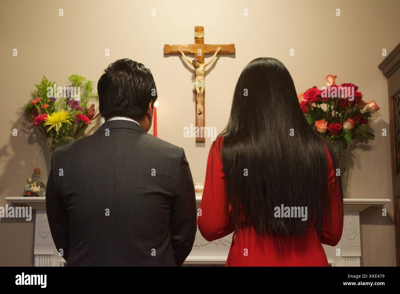 Matura in piedi presso l'altare di fronte a un Crocifisso durante la cerimonia Foto Stock