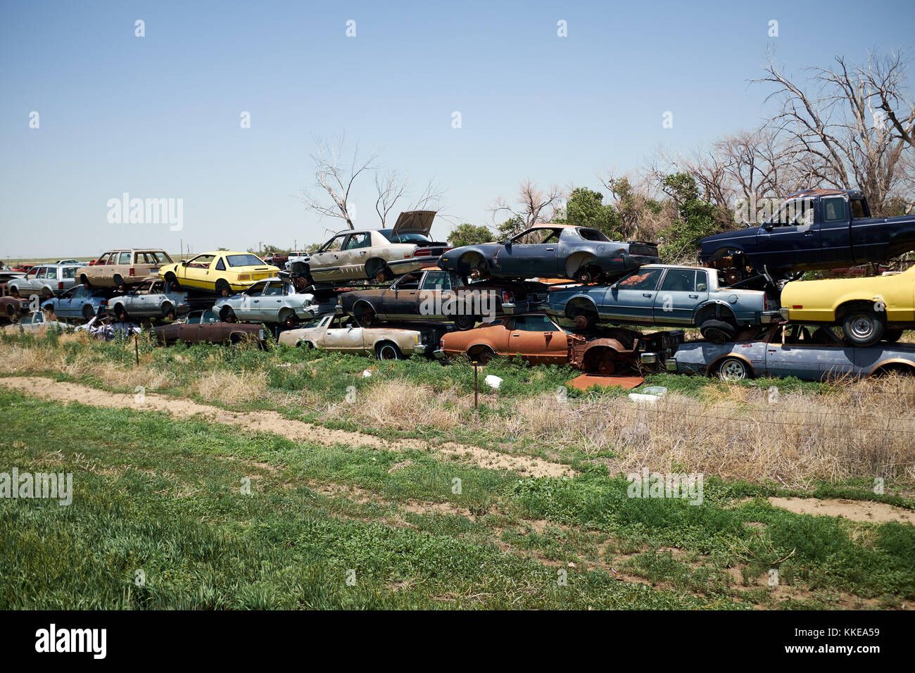 Lungo la linea del vecchio obsoleto arrugginendo auto accatastate in un cantiere di scarto o breaker cantiere in attesa di essere schiacciato e riciclato o rotte per le parti di ricambio Foto Stock