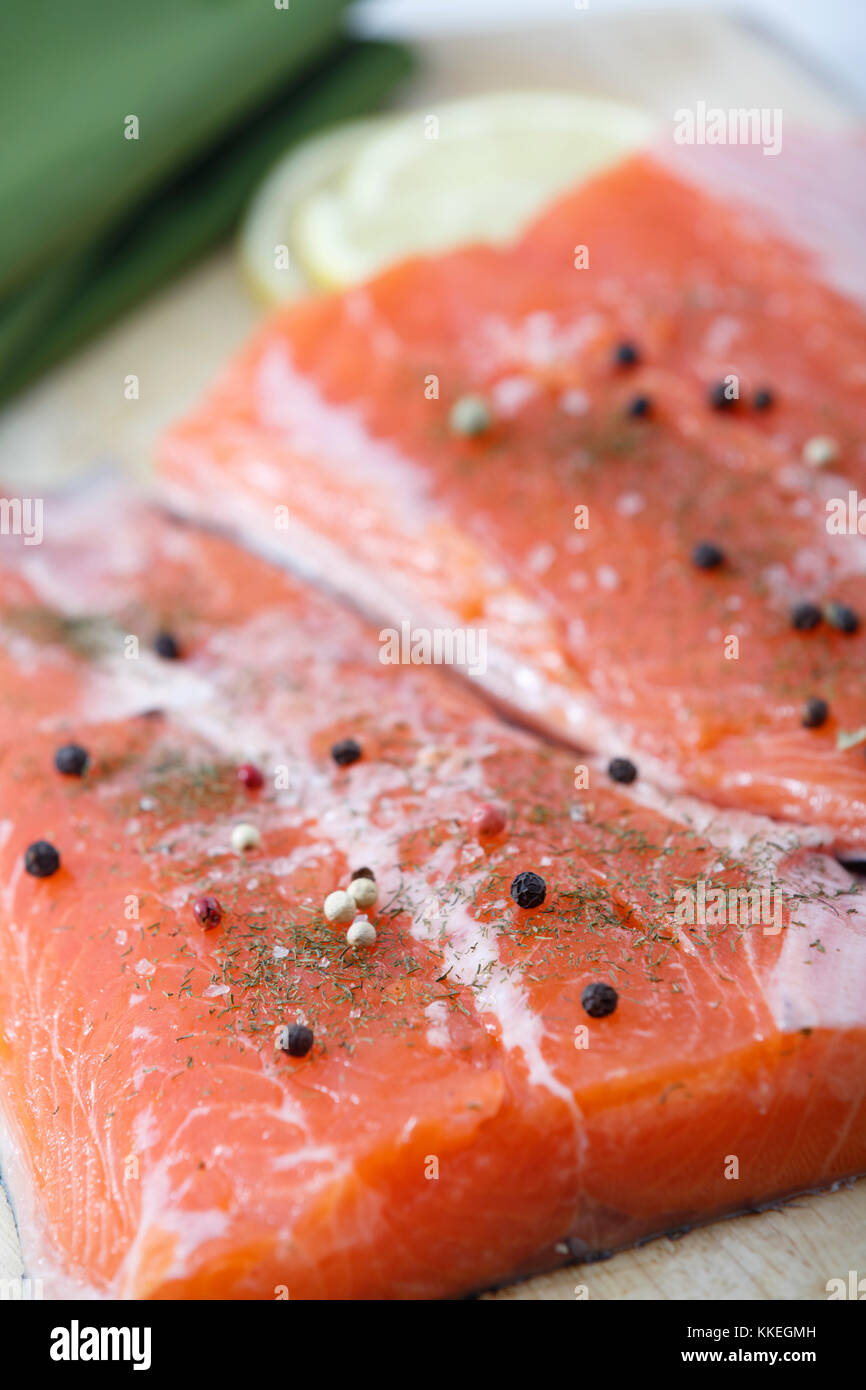 Due materie pezzi di salmone pronto su un tagliere. La messa a fuoco è di sinistra sul filetto. Foto Stock