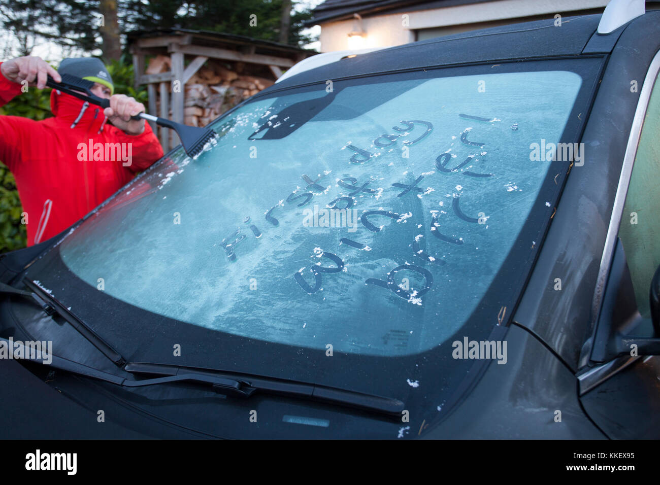 Flintshire, Nord, Regno Unito meteo. artic chill e condizioni di congelamento rimangono ancora su molte parti del regno unito oggi il primo giorno di inverno secondo il calendario meteorologico. Un uomo ghiaccio di compensazione di un parabrezza congelata con le parole primo giorno di inverno scritto nel ghiaccio prima del suo treno di Flintshire, Galles Foto Stock
