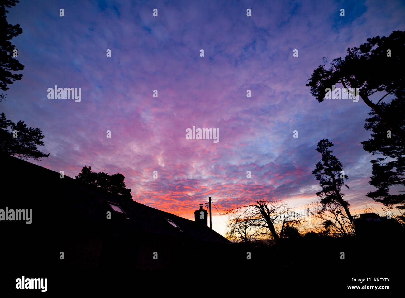 Flintshire, Nord, Regno Unito. il meteo. artic chill e condizioni di congelamento rimangono ancora su molte parti del regno unito oggi il primo giorno di inverno secondo il calendario meteorologico con una probabilità di pioggia per molti domani. il tramonto su un gallese cottage lungo nel villaggio di lixwm come il sole tramonta overhead al termine del primo giorno di inverno secondo il calendario meteorologico. Foto Stock